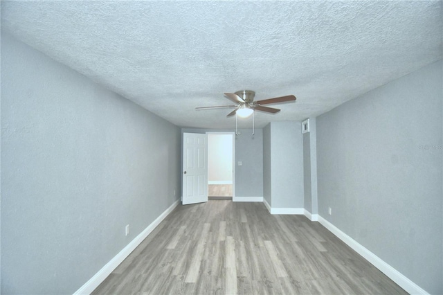 spare room with a textured ceiling, light hardwood / wood-style floors, and ceiling fan