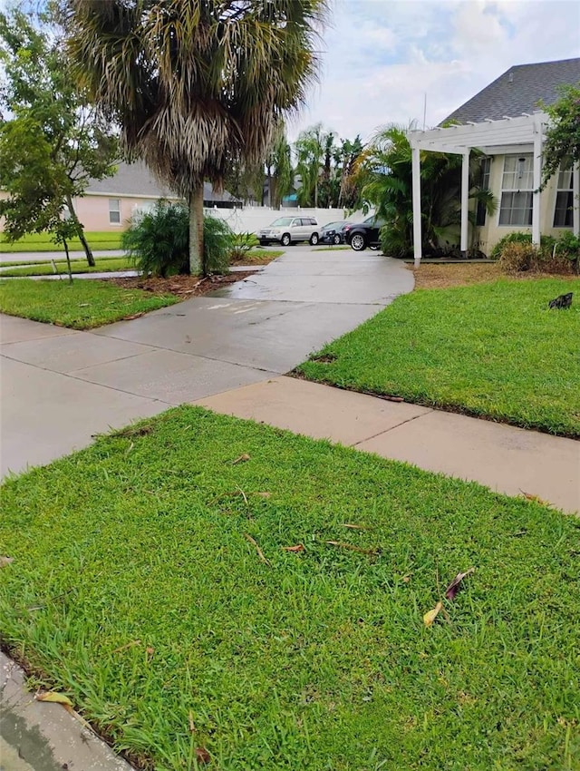 view of yard with driveway and a pergola