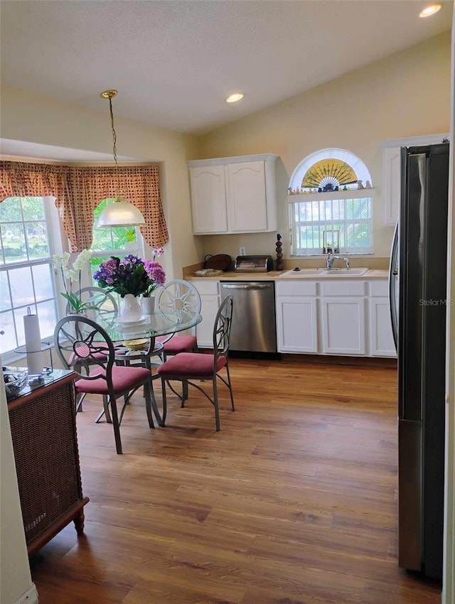 kitchen featuring black fridge, pendant lighting, stainless steel dishwasher, and white cabinets