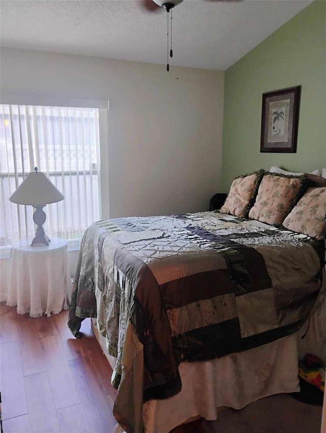 bedroom with wood-type flooring, ceiling fan, and lofted ceiling