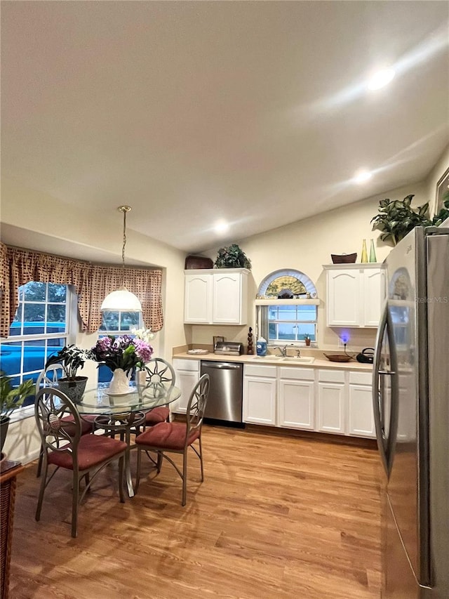 kitchen with stainless steel appliances, light wood-type flooring, pendant lighting, sink, and white cabinets