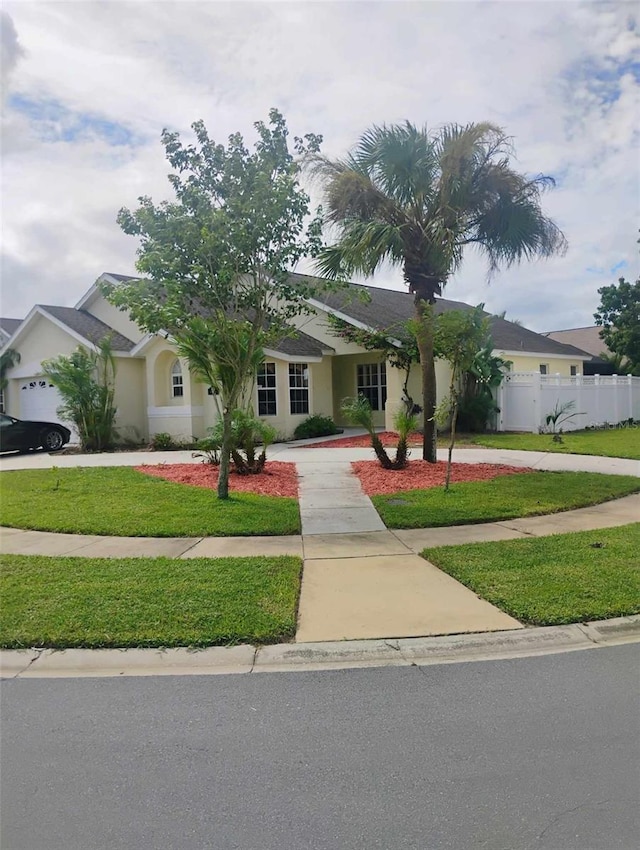 view of front of house featuring concrete driveway, fence, a front lawn, and stucco siding