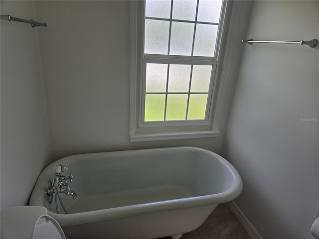 bathroom featuring tile patterned floors, a bathtub, and toilet