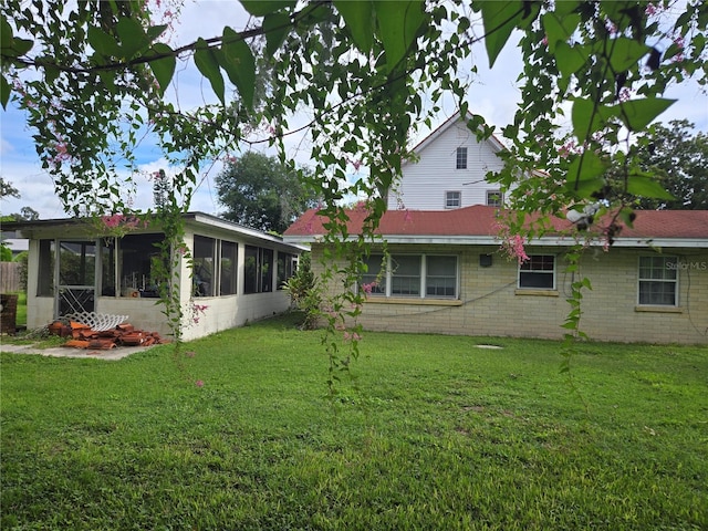 rear view of house with a lawn and a sunroom