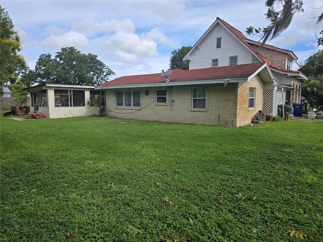 back of property with a lawn and a sunroom