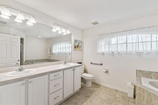 bathroom featuring vanity, a relaxing tiled tub, toilet, and a healthy amount of sunlight