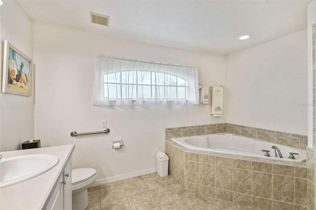 bathroom with tiled tub, vanity, toilet, and tile patterned flooring