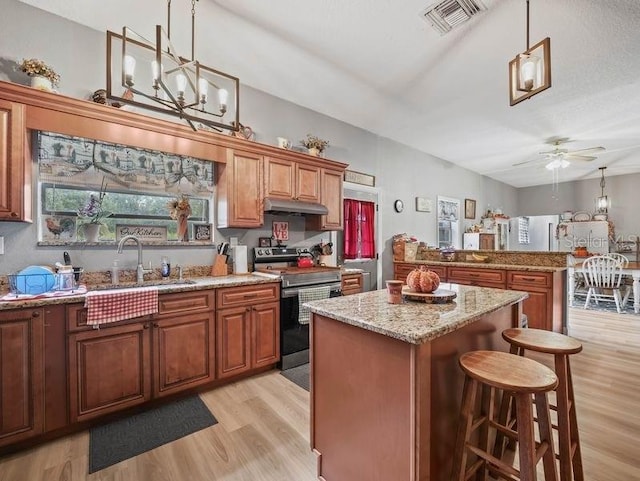 kitchen with a breakfast bar area, light wood-type flooring, a center island, sink, and stainless steel electric range oven