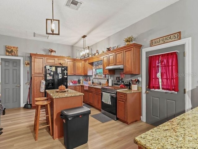 kitchen featuring pendant lighting, stainless steel electric range oven, a kitchen island, light hardwood / wood-style flooring, and black fridge with ice dispenser