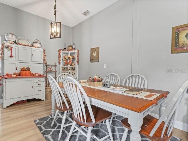 dining area with lofted ceiling, light hardwood / wood-style flooring, and a notable chandelier