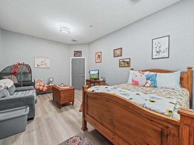 bedroom featuring light wood-type flooring and a textured ceiling