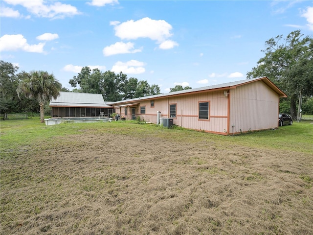 rear view of property with a yard and central AC unit