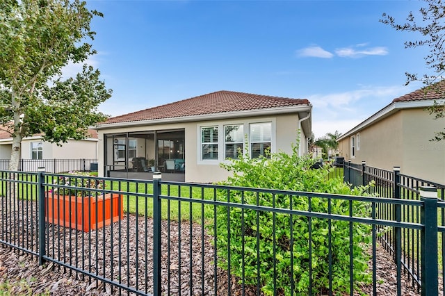 rear view of house featuring a sunroom and a lawn