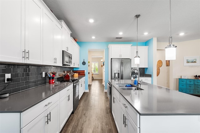 kitchen with pendant lighting, dark wood-type flooring, sink, stainless steel appliances, and white cabinets