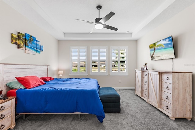 carpeted bedroom featuring ceiling fan and a raised ceiling