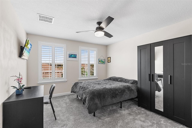 bedroom featuring light colored carpet, a textured ceiling, and ceiling fan