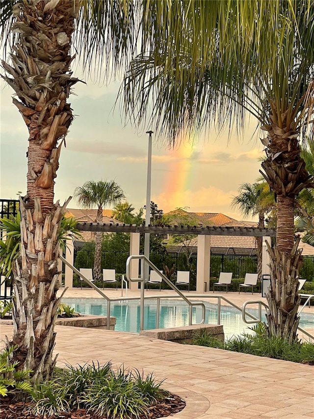 pool at dusk with a patio area