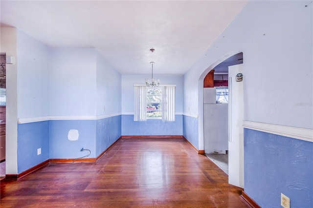 empty room featuring dark wood-type flooring and an inviting chandelier