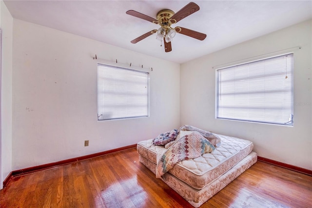 bedroom with multiple windows, ceiling fan, and hardwood / wood-style floors