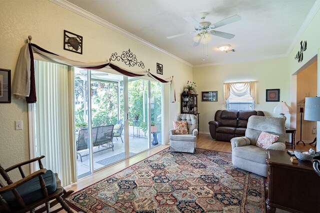 living room featuring wood-type flooring, ornamental molding, and ceiling fan