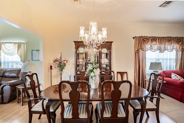 dining space featuring a chandelier, light hardwood / wood-style floors, and crown molding