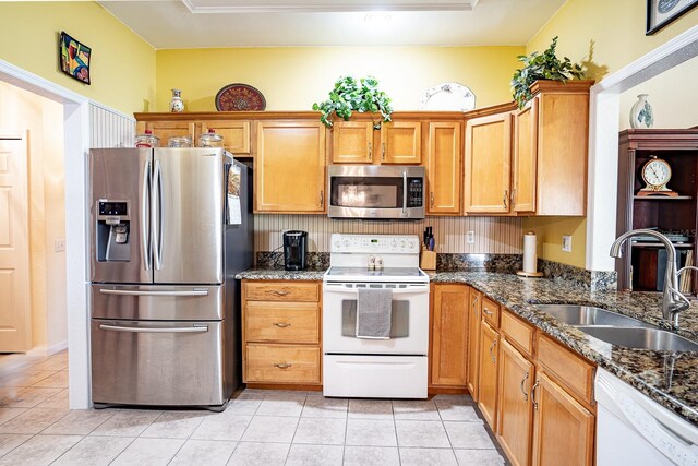 kitchen featuring appliances with stainless steel finishes, dark stone counters, sink, and light tile patterned floors