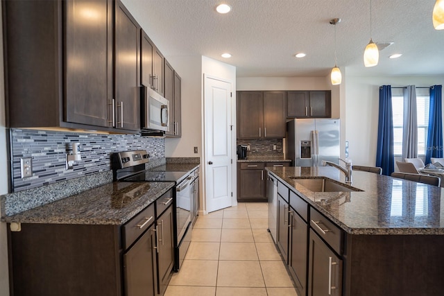 kitchen with appliances with stainless steel finishes, hanging light fixtures, a textured ceiling, and sink