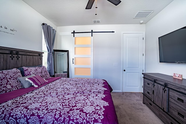 bedroom with dark carpet, a textured ceiling, ceiling fan, and a barn door