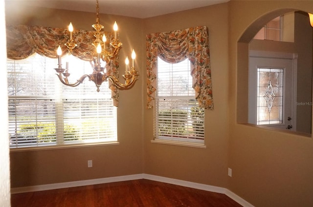 empty room with wood-type flooring and a notable chandelier