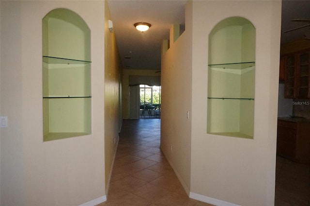 hallway with built in features and tile patterned floors