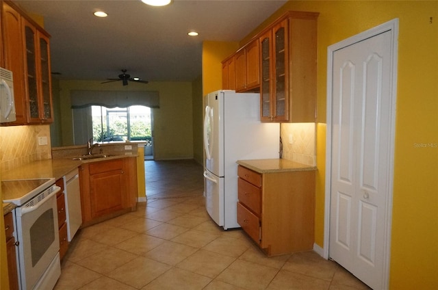 kitchen with sink, tasteful backsplash, light tile patterned floors, kitchen peninsula, and white appliances