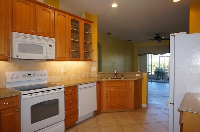 kitchen with sink, decorative backsplash, white appliances, and kitchen peninsula