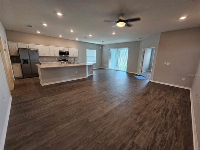 kitchen with an island with sink, white cabinets, appliances with stainless steel finishes, and dark hardwood / wood-style floors