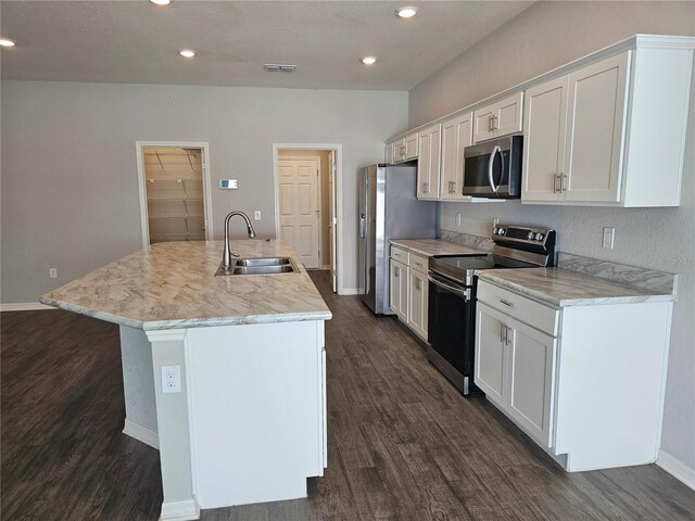 kitchen with dark wood-type flooring, sink, an island with sink, white cabinets, and stainless steel appliances