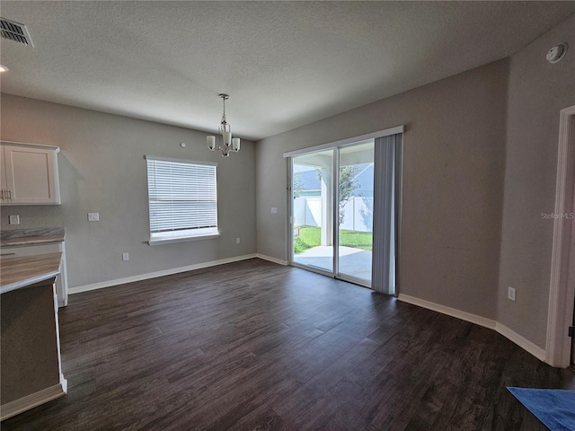 unfurnished dining area featuring a notable chandelier, a textured ceiling, and dark hardwood / wood-style flooring