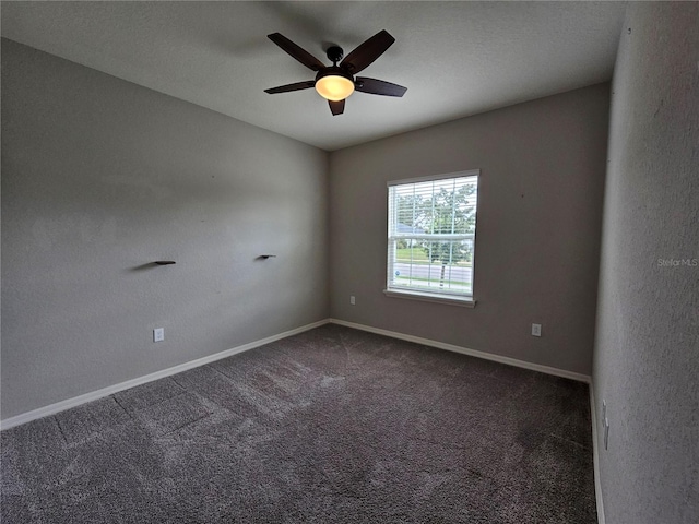 empty room featuring dark carpet and ceiling fan