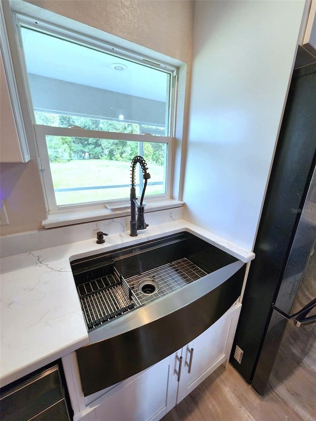 room details with light hardwood / wood-style floors, refrigerator, sink, and white cabinets