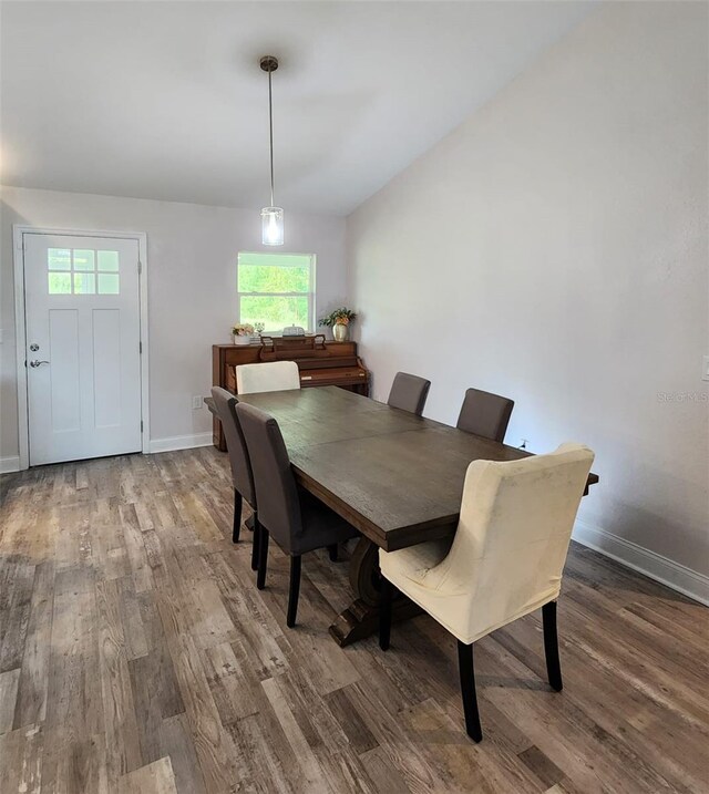 dining room featuring hardwood / wood-style flooring, plenty of natural light, and vaulted ceiling