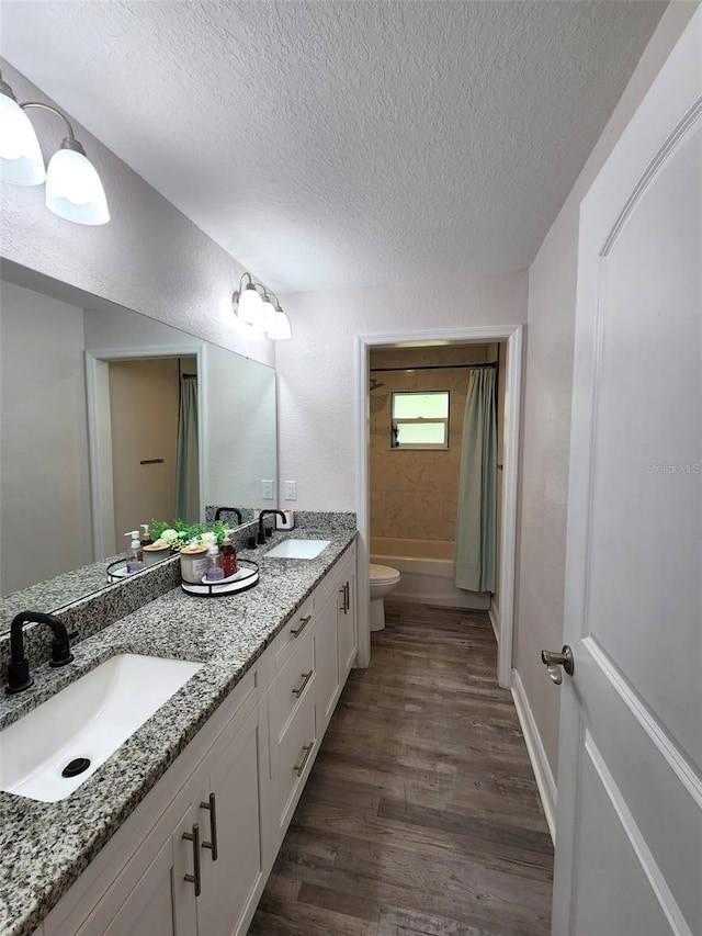 full bathroom with toilet, wood-type flooring, vanity, a textured ceiling, and shower / bathtub combination with curtain