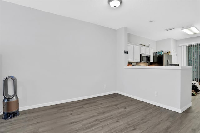 kitchen featuring kitchen peninsula, dark wood-type flooring, stainless steel appliances, and white cabinets