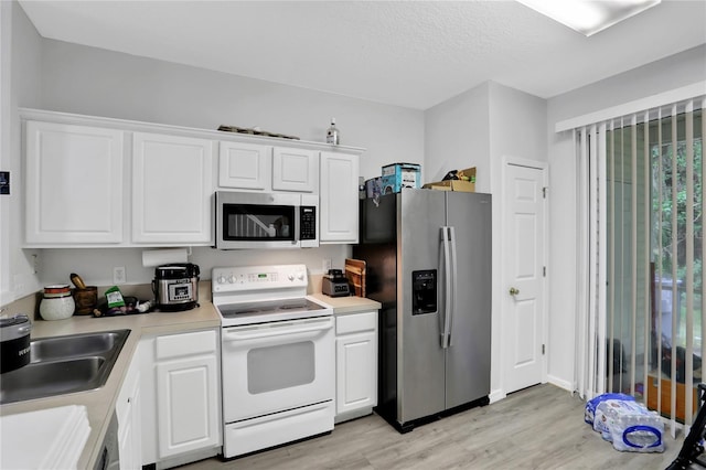 kitchen featuring white cabinets, stainless steel appliances, and light wood-type flooring