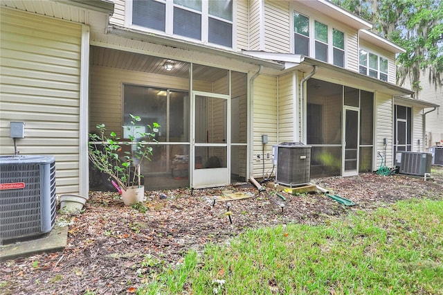 rear view of house with central AC unit and a sunroom