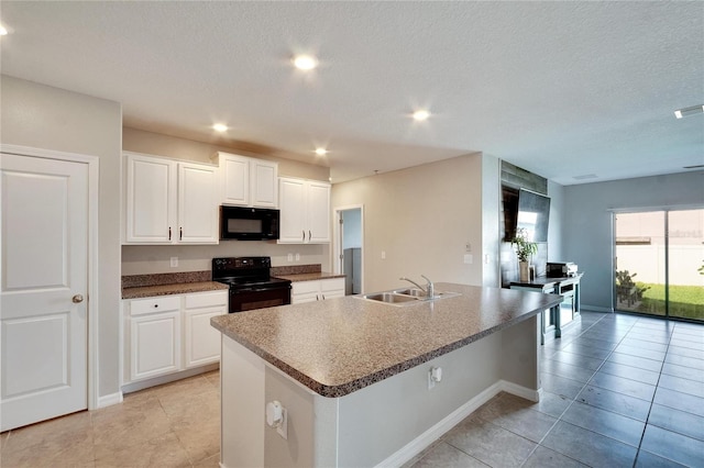 kitchen with a textured ceiling, a kitchen island with sink, white cabinetry, and black appliances