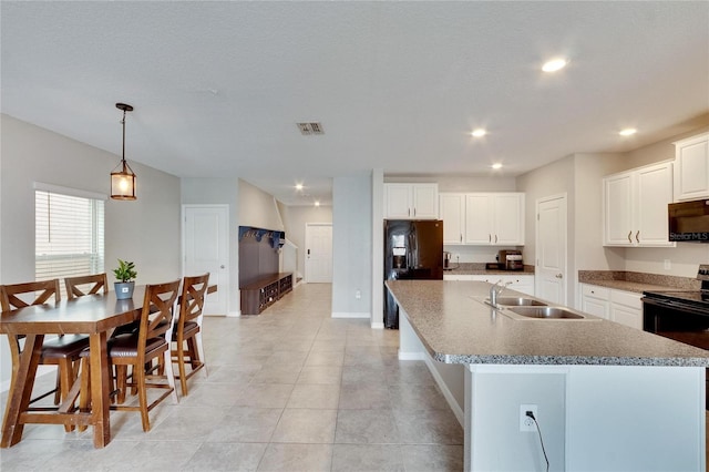 kitchen featuring white cabinets, black appliances, decorative light fixtures, a center island with sink, and sink