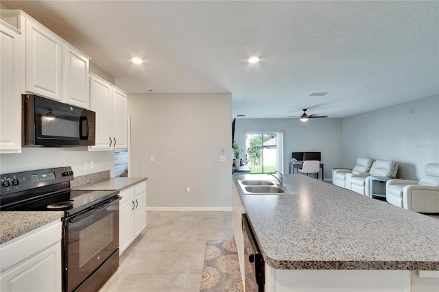 kitchen with black appliances, a center island with sink, sink, and white cabinets