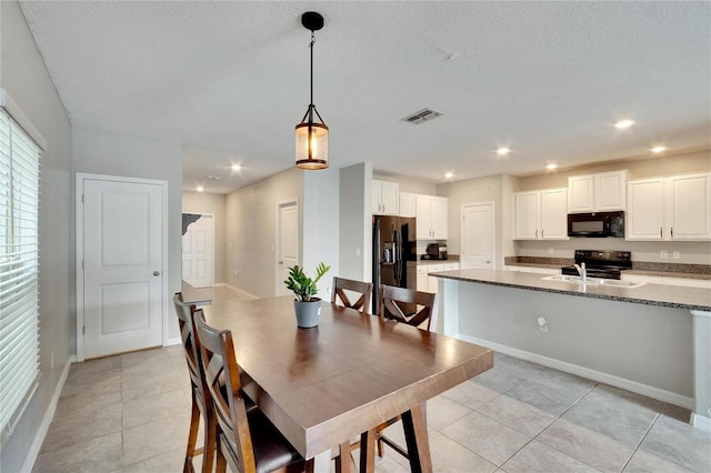 tiled dining room with a textured ceiling and sink