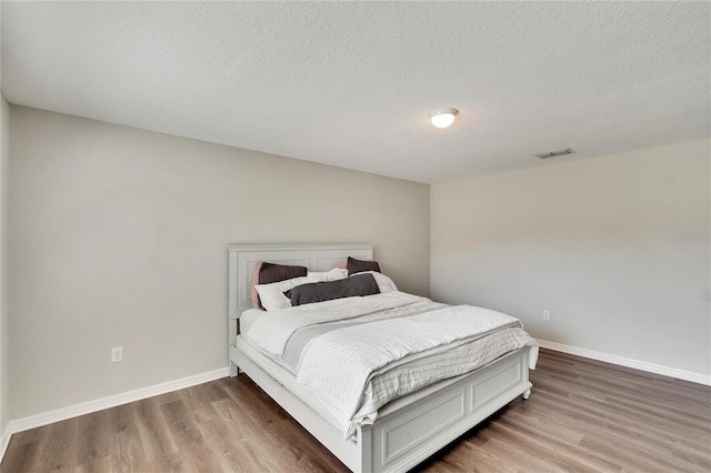 bedroom featuring wood-type flooring and a textured ceiling