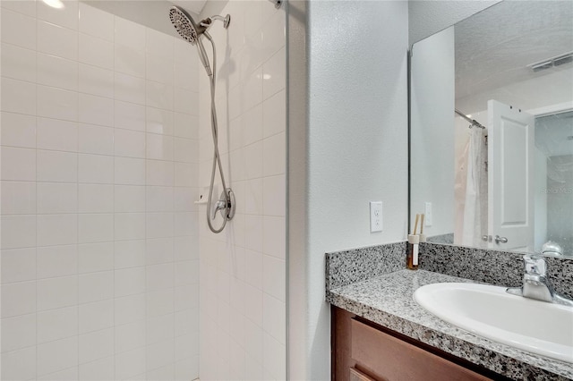 bathroom with a textured ceiling, vanity, and curtained shower