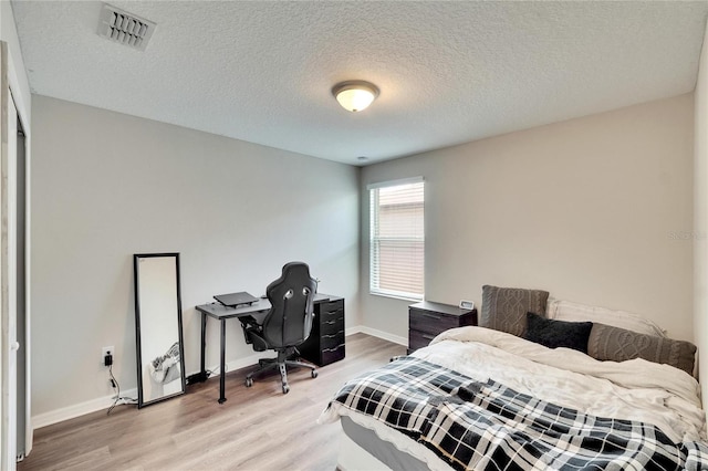 bedroom featuring a textured ceiling and light hardwood / wood-style flooring