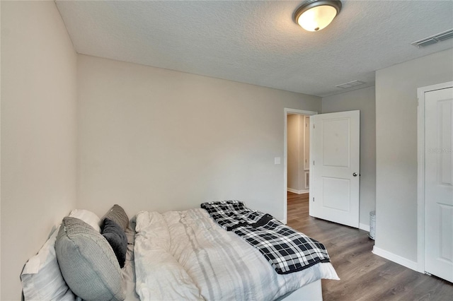 bedroom with a textured ceiling and dark wood-type flooring